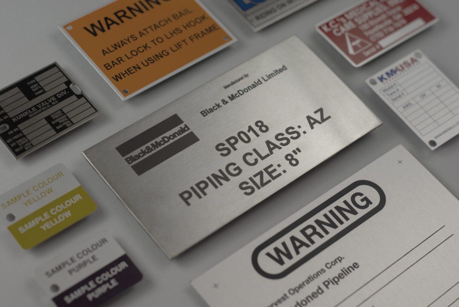 A variety of different sized stainless steel conduit tags displaying different information on each showcasing the variety