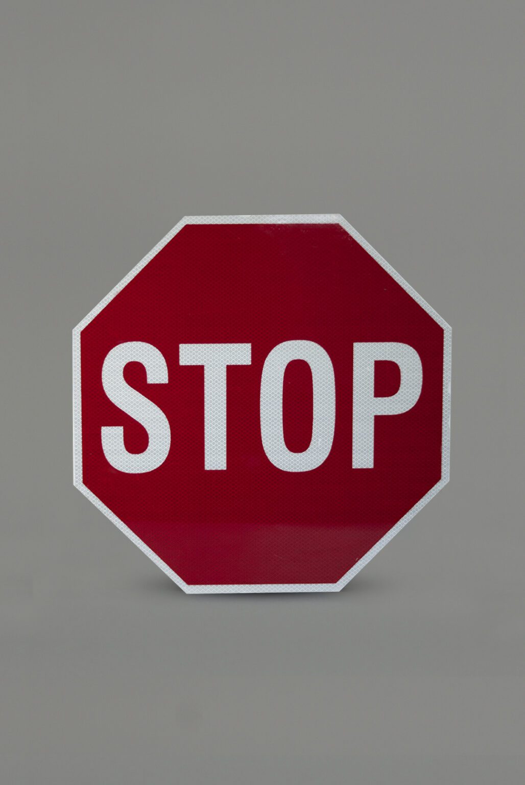 A red stop sign against a clean gray background