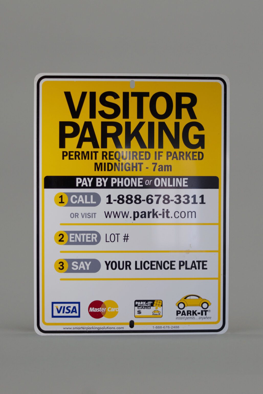 A visitor parking signs displaying the different rules and regulations about parking in that particular spot including phone numbers websites, reminder of license plate and payment options