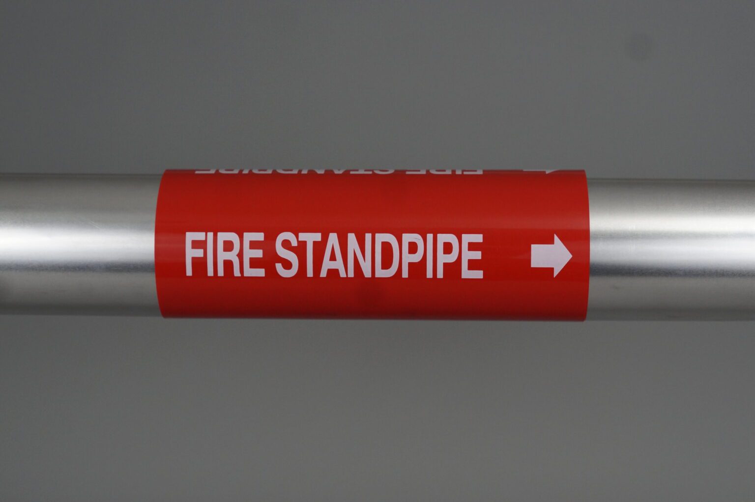 A red coiled pipe marker wrapped around a steel pipe. The legend reads fire standpipe with an arrow pointing to the left.
