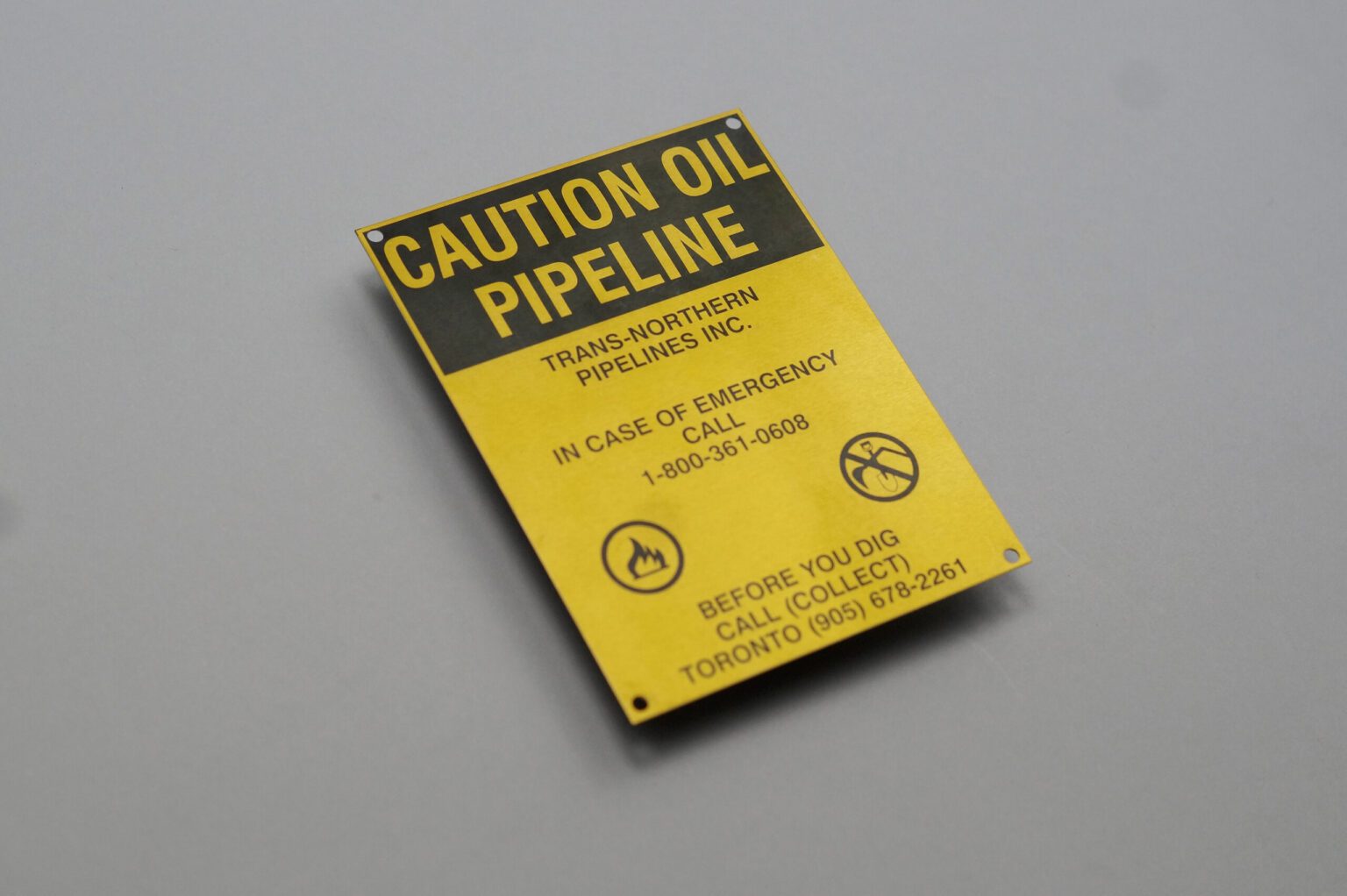 A yellow rectangular sign that reads caution oil pipeline with various information describing the danger you may encounter