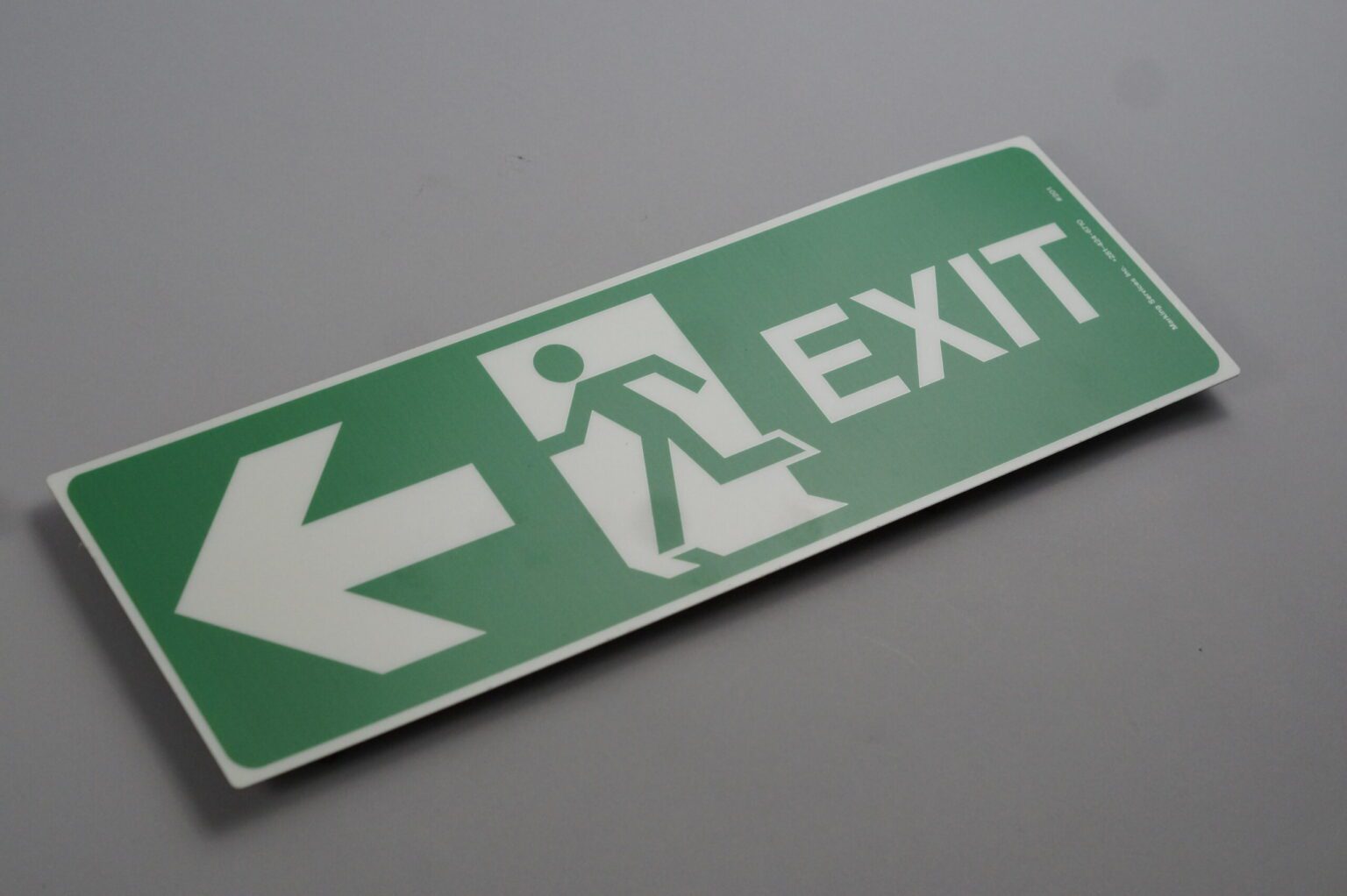 A rectangular exit sign that depicts an arrow a man running through a door and the word "exit"