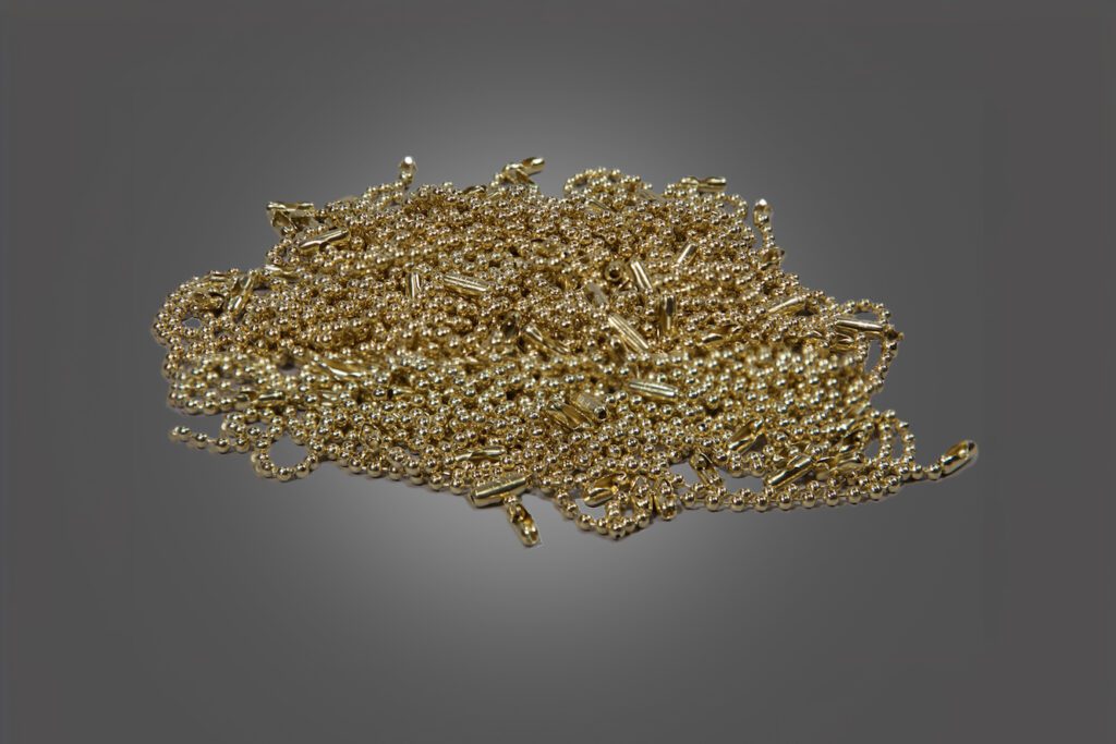 A pile of gold beaded chains against a clean gray background