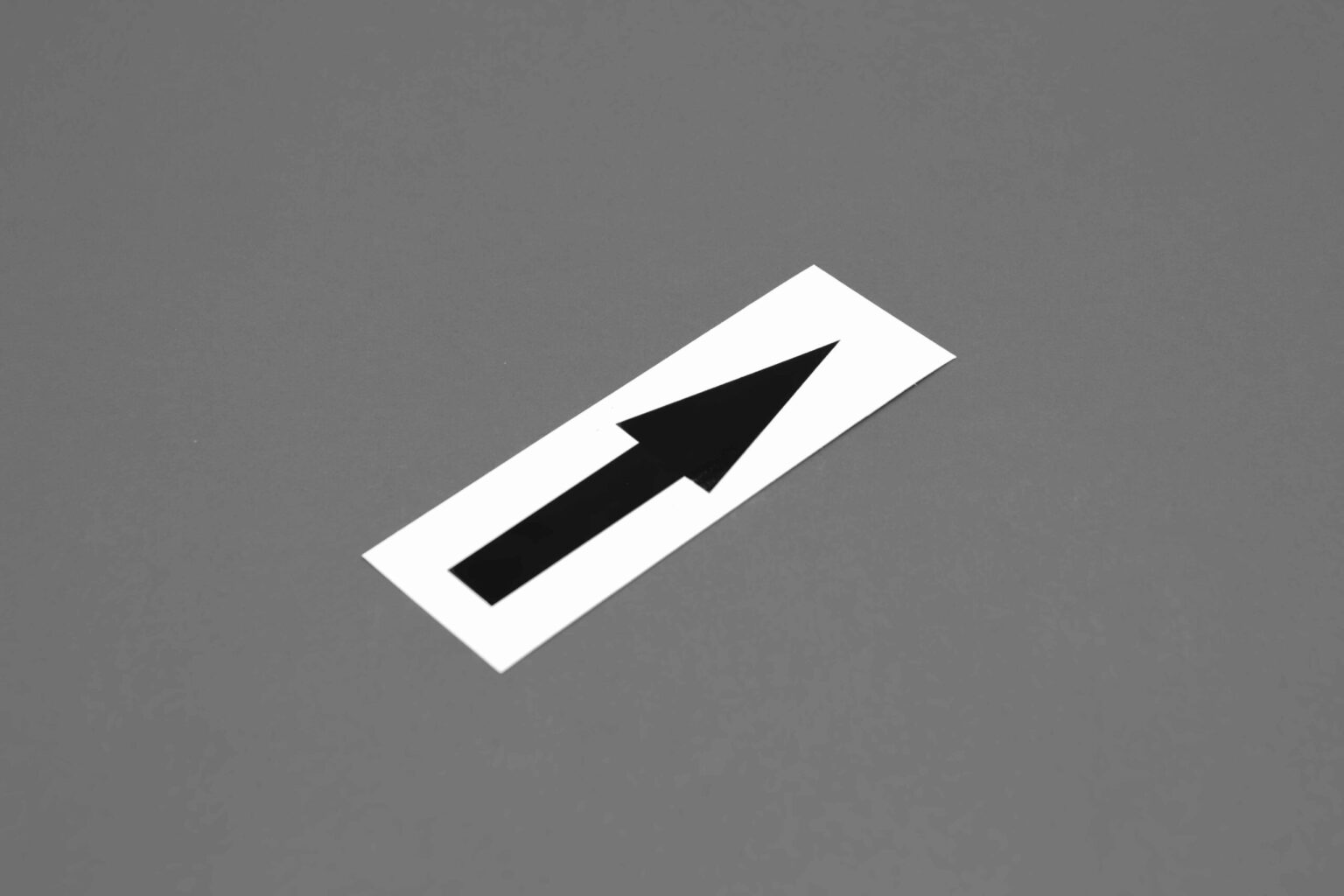 A white sticker on a 45° angle with a big black arrow pointing up