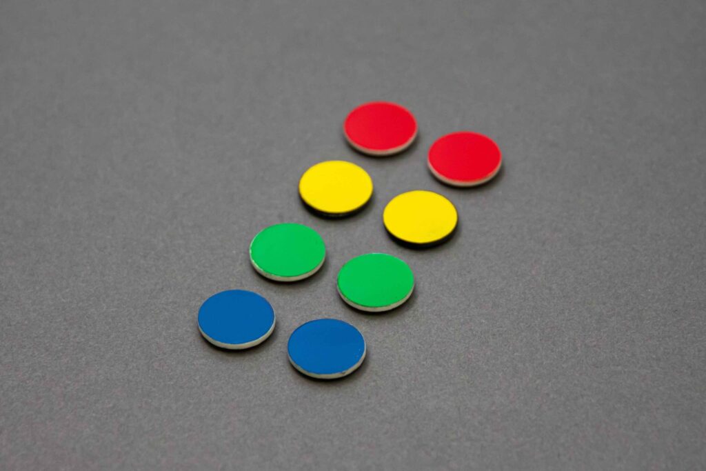 Two rows of red yellow green and blue locator dots sit in Paris at a 45° angle on a clean gray background