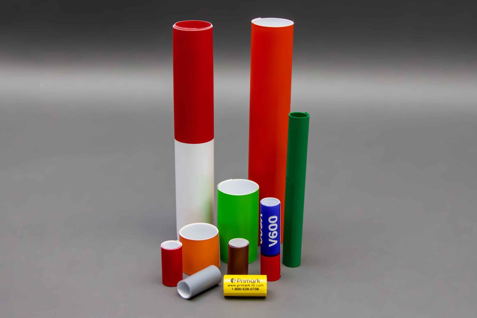 10 coiled conduit markers of various sizes and colors are displayed nicely against a clean gray background some have Legends on them but most of them do not this photo showcases the material and how they can be wrapped around pipes