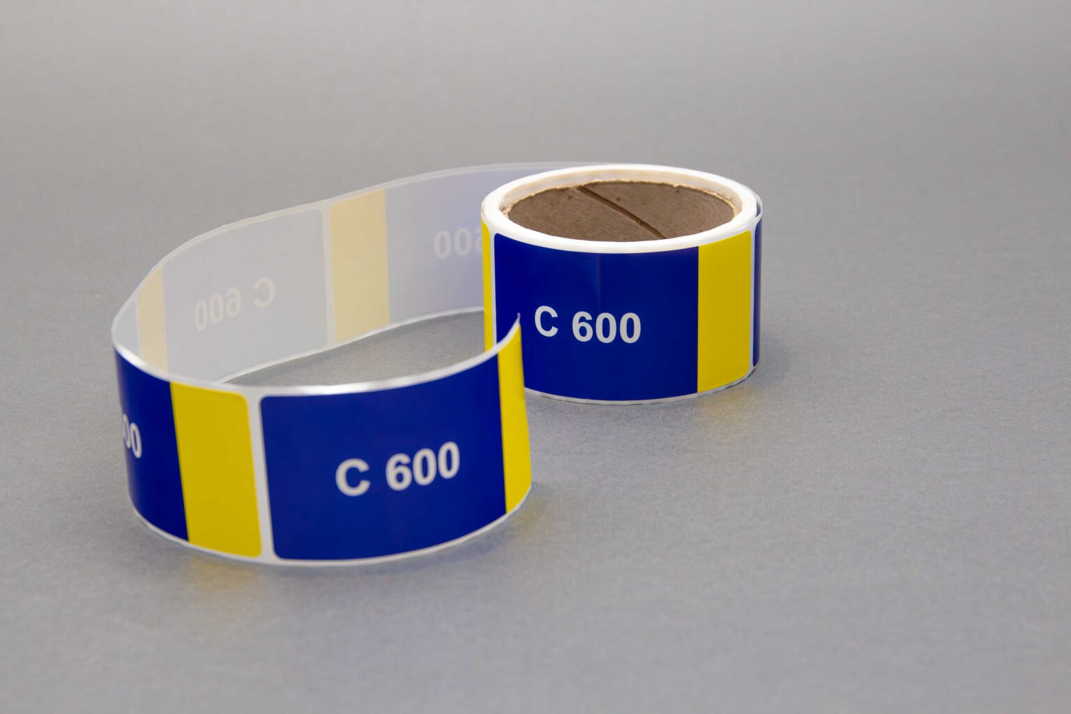 A blue and yellow sticker roll that reads c600 on every sticker on a clean gray background