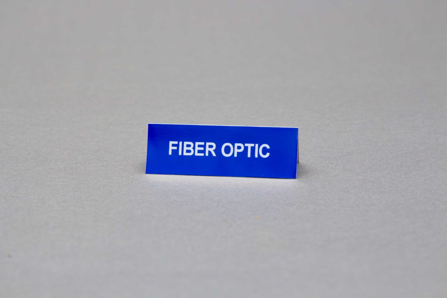 A small blue adhesive conduit marker sticker that reads "fiber optic"
