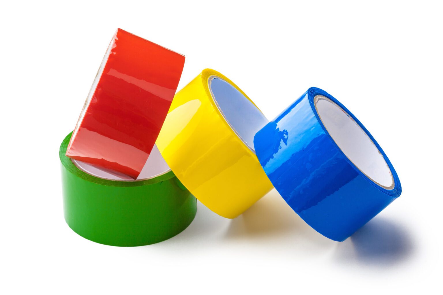 Four rules of banding tape are displayed nicely against a clean white background the first is Green the second is red the third is yellow and the last is blue. The green is lying flat on the ground the red is resting on a slight angle on top of the green and the blue and yellow are leaning up against the Green and the red