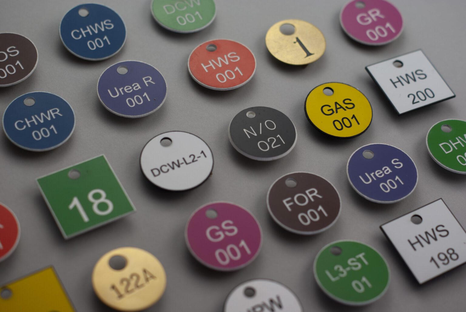 A beautiful display of multiple circular and square valve tags in various sizes and colors displaying the variety