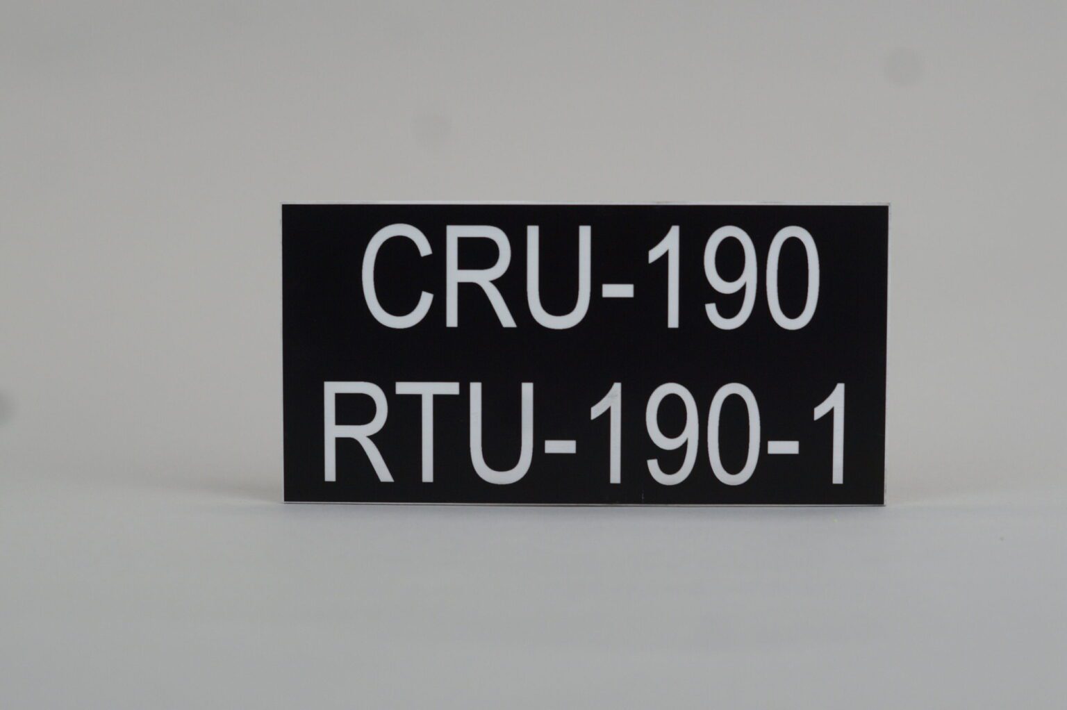 A black lamacoid with white text that reads "cru 190 rtu-190-1