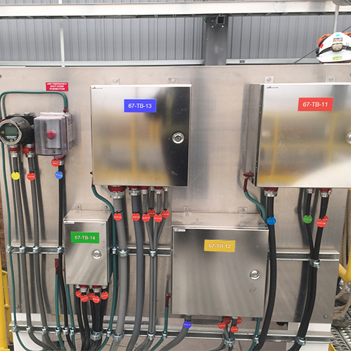 A series of industrial boxes panels controls and wires all carefully labeled in colorful equipment tags and lamicoids